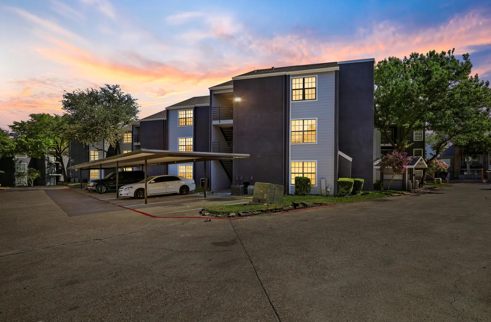 Village Oaks apartment building at sunset with covered parking