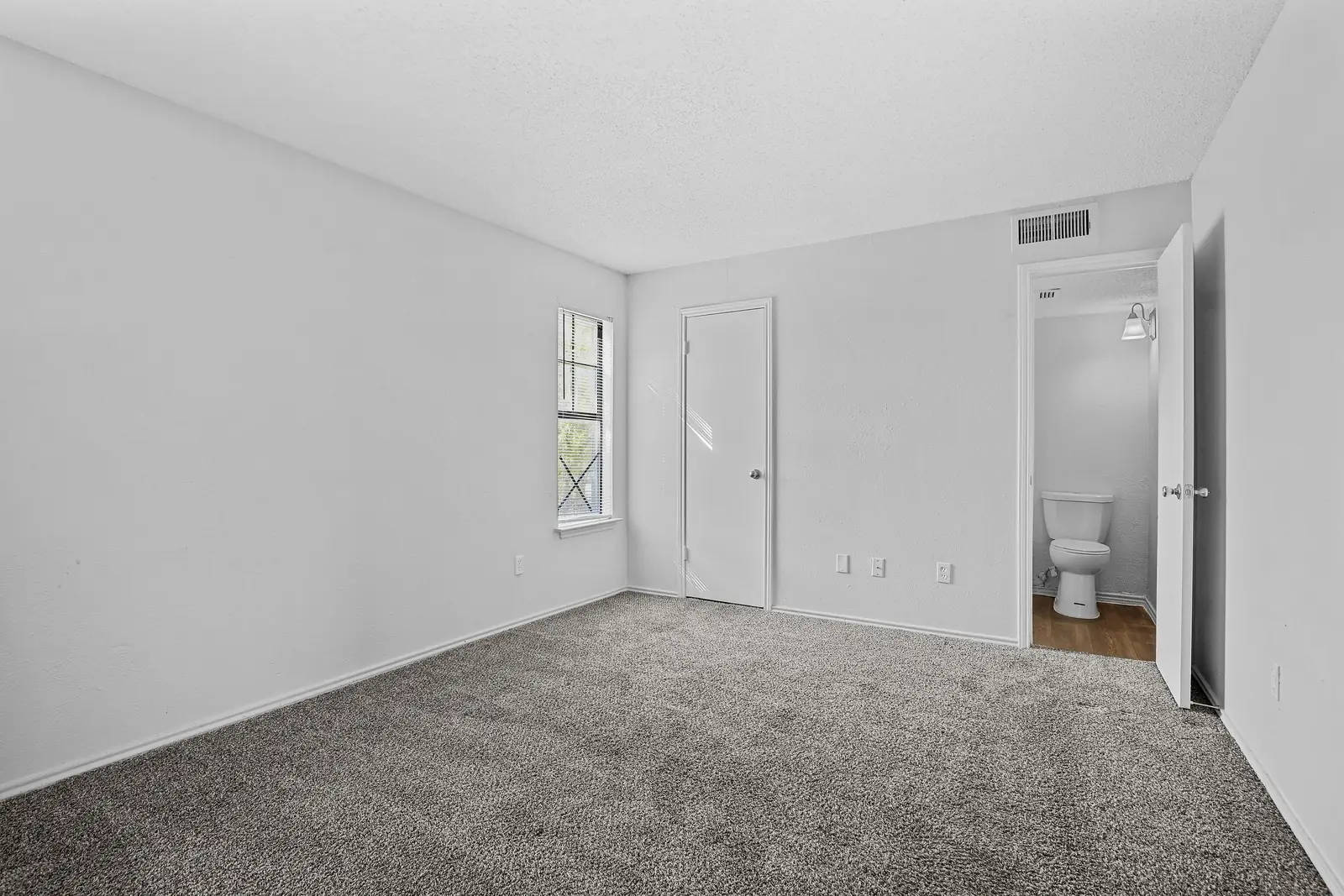 Carpeted bedroom with window and adjoining bath